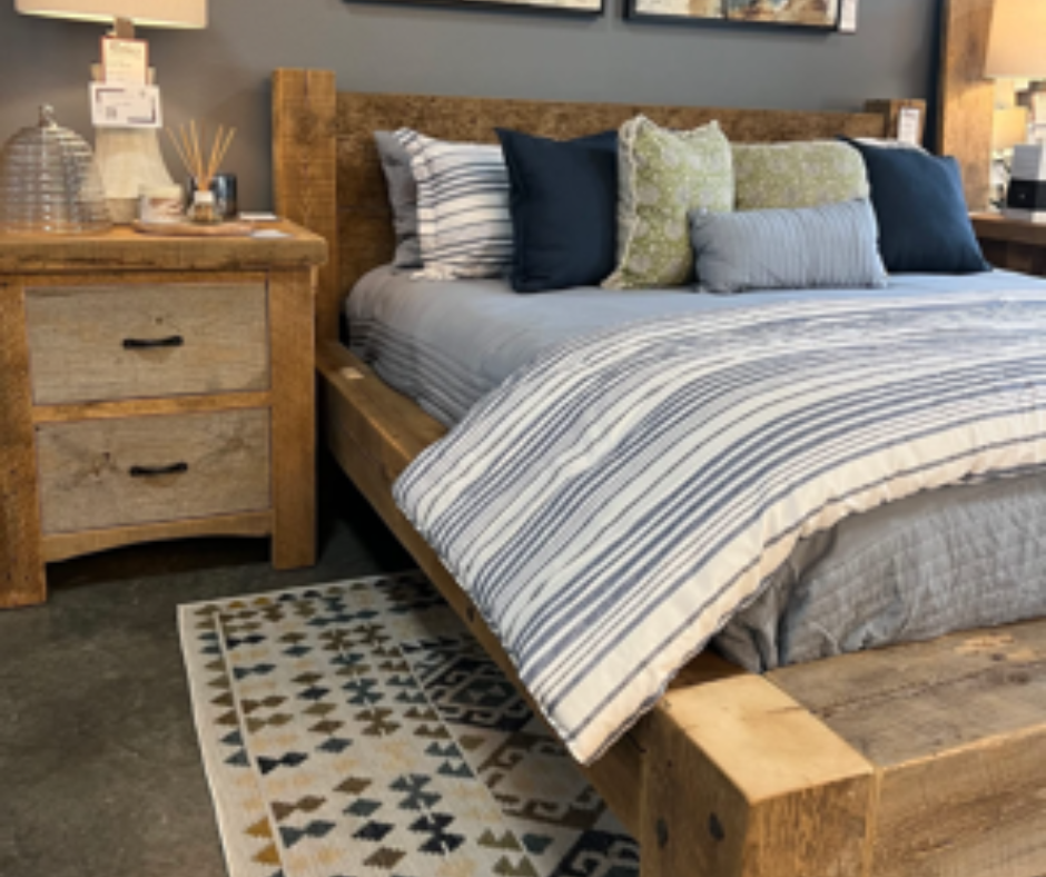 Rustic bedroom with solid wood bed frame, cozy striped bedding, decorative pillows, and matching wooden nightstand.